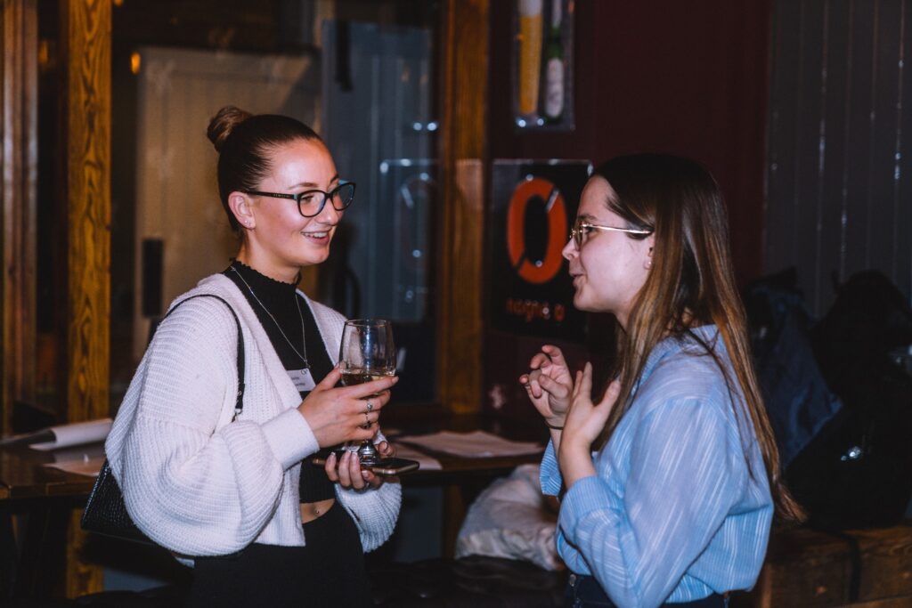 2 girls speaking to one another at an event